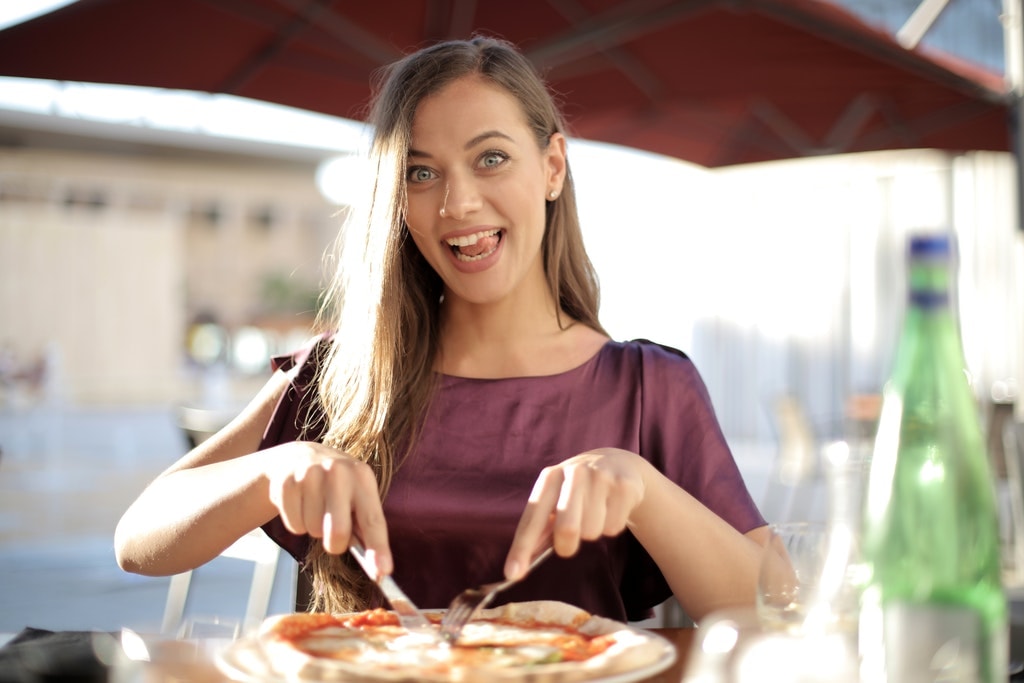 photo-of-woman-in-purple-top-while-slicing-pizza